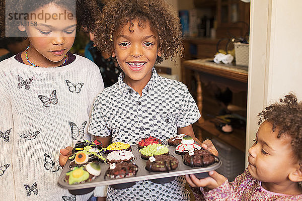 Porträt glücklicher Junge mit dekorierten Halloween-Cupcakes
