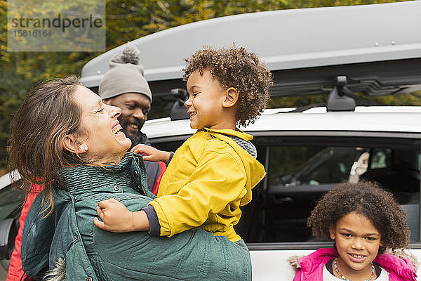 Glückliche Familie umarmt außerhalb Auto auf dem Parkplatz