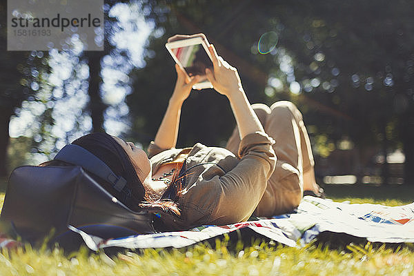 Junge Frau benutzt digitales Tablet in einem sonnigen Sommerpark