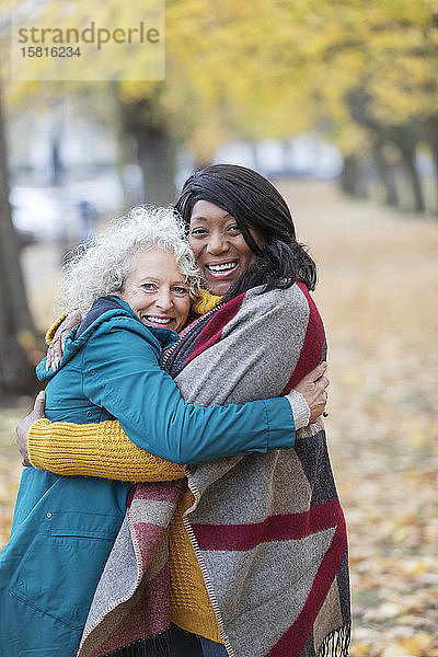 Enthusiastische ältere Frauen umarmen sich im Herbst im Park