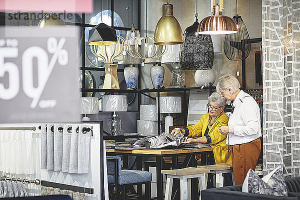 Ältere Frauen beim Einkaufen und Betrachten von Stoffmustern in einem Geschäft für Wohnkultur