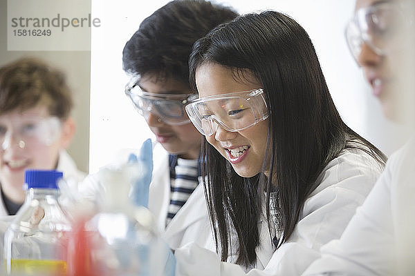 Lächelndes Mädchen bei der Durchführung eines wissenschaftlichen Experiments in einem Klassenzimmer