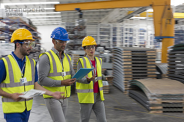 Vorgesetzter und Arbeiter mit Klemmbrett und digitalem Tablet in der Fabrik