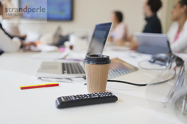 Einweg-Kaffeebecher und Fernbedienung auf dem Tisch im Konferenzraum