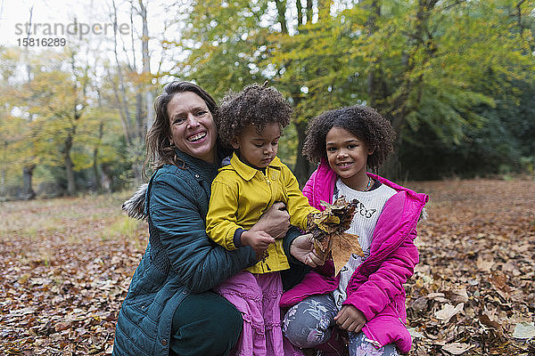 Porträt glückliche Mutter und Töchter spielen im Herbst Blätter im Wald