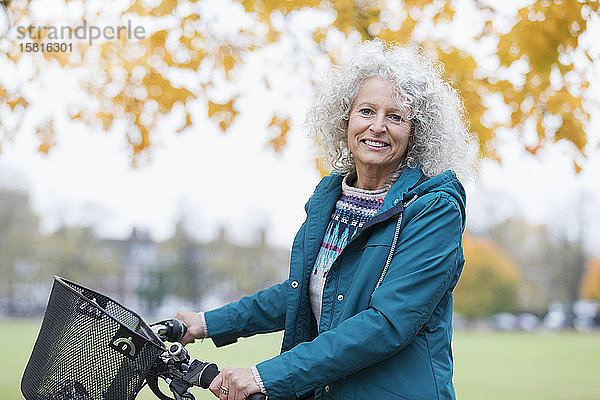 Porträt zuversichtlich  lächelnd ältere Frau Fahrradfahren im Herbst Park