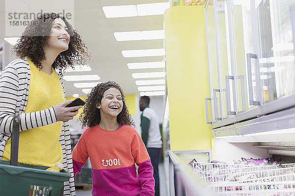 Glückliche Mutter und Tochter beim Einkaufen von Tiefkühlkost im Supermarkt