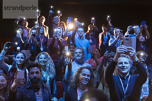 Gespanntes Publikum mit Smartphone-Taschenlampen im dunklen Hörsaal