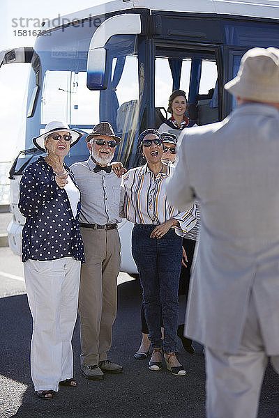 Lächelnde  aktive Seniorenfreunde  die vor einem Reisebus stehen