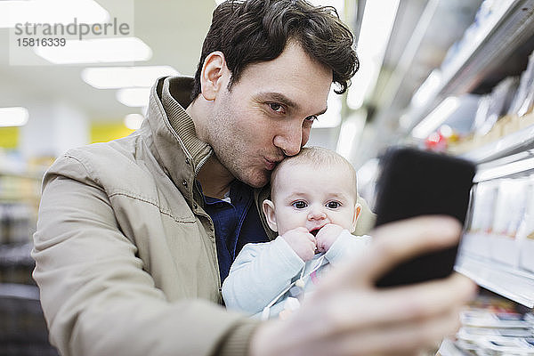 Zärtlicher Vater und kleine Tochter machen ein Selfie im Supermarkt