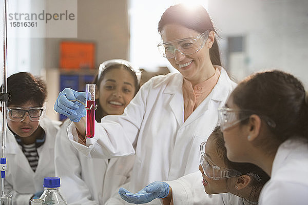 Lächelnde Chemielehrerin und Studenten  die ein wissenschaftliches Experiment im Labor durchführen