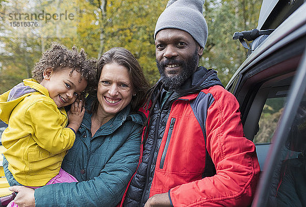 Porträt einer glücklichen multiethnischen Familie  die vor einem Auto steht