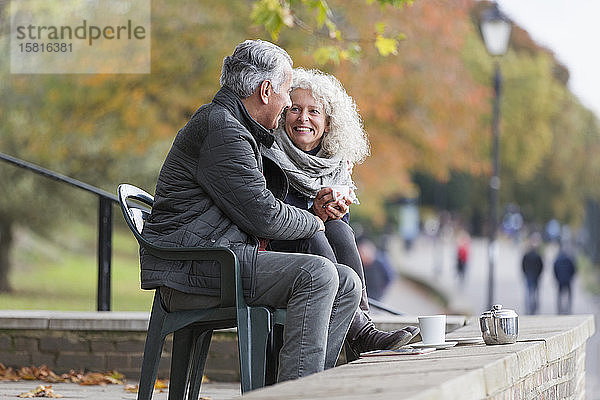 Lächelndes  liebevolles  aktives Seniorenpaar beim Teetrinken im Herbstpark