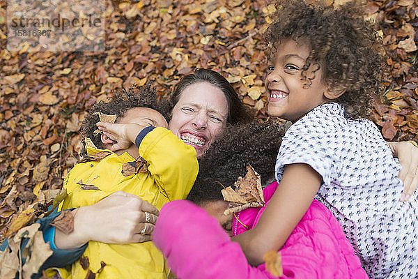 Porträt glückliche Mutter und Kinder spielen im Herbst Blätter