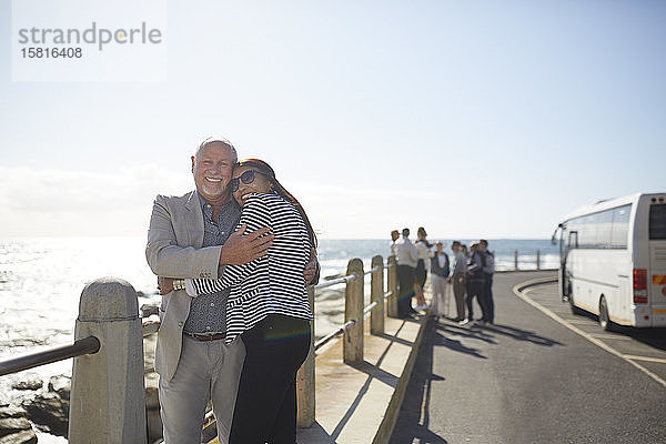 Porträt aktives älteres Paar Touristen  die sich an einem sonnigen Aussichtspunkt am Meer umarmen