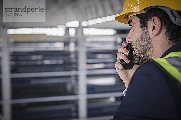 Männlicher Vorgesetzter  der ein Walkie-Talkie in einer Fabrik benutzt