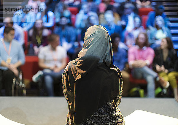 Weibliche Rednerin im Hidschab auf der Bühne spricht zum Publikum