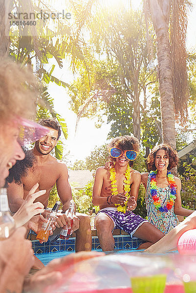 Junge Freunde  die im sonnigen Sommerschwimmbad abhängen  reden und trinken