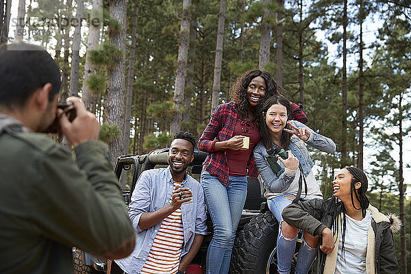 Junger Mann mit Digitalkamera fotografiert Freunde im Jeep im Wald