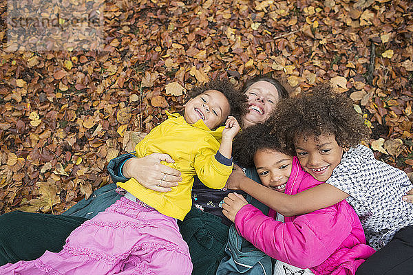 Porträt glückliche Mutter und Kinder liegen im Herbstlaub