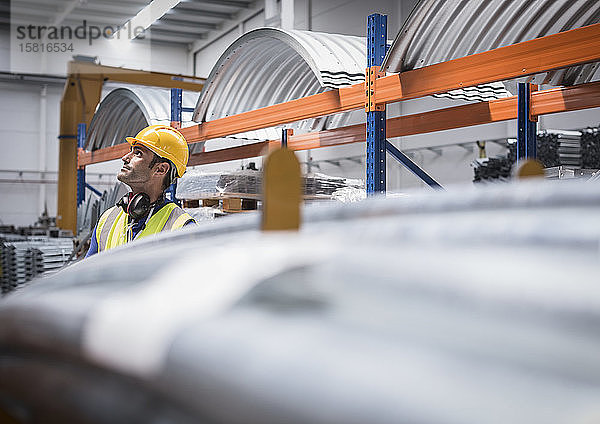 Männlicher Arbeiter  der in einer Stahlfabrik nach oben schaut