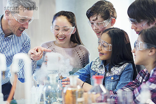 Männlicher Lehrer und Schüler  die eine chemische Reaktion beobachten und ein wissenschaftliches Experiment in einem Klassenzimmer durchführen