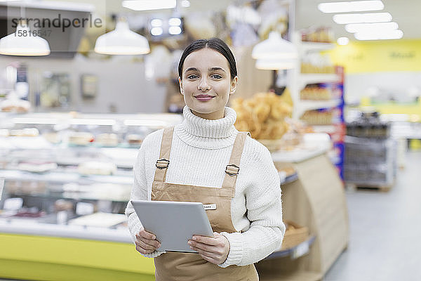 Porträt einer selbstbewussten Lebensmittelhändlerin mit digitalem Tablet im Supermarkt