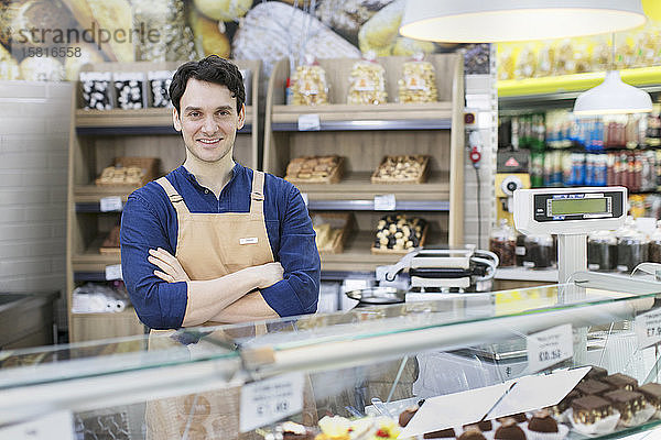 Porträt selbstbewusster männlicher Arbeiter hinter einer Bäckereivitrine im Supermarkt