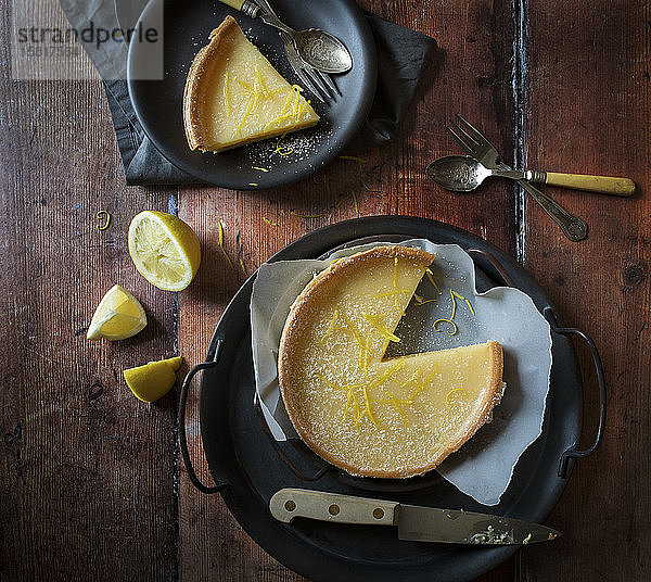 Zitronenkuchen mit herausgenommener Scheibe Scheibe auf Teller mit Zitronen
