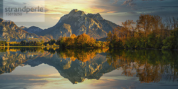 Deutschland  Bayern  Hohenschwangau  See Forggensee  in dem sich in der Herbstdämmerung die umliegenden Bäume und Hügel spiegeln