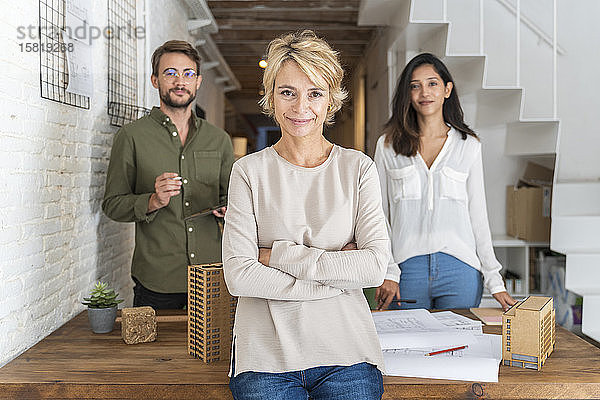 Porträt einer selbstbewussten reifen Frau im Architekturbüro mit Kollegen im Hintergrund