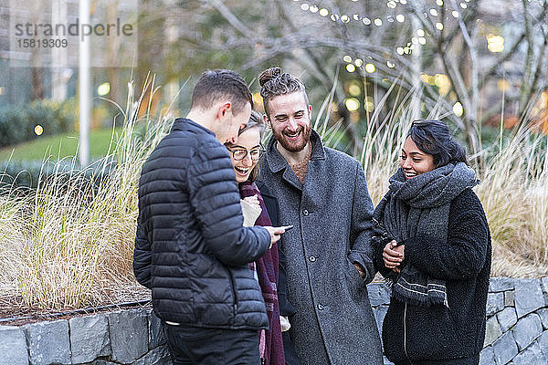 Glückliche Freunde schauen auf Smartphones in der Stadt