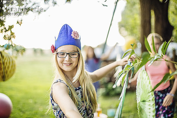 Mädchen mit Partyhut schmückt den Garten für eine Geburtstagsfeier