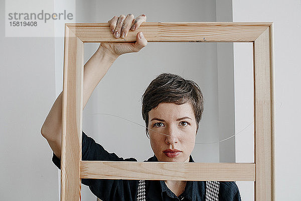 Porträt einer Malerin  die in ihrem Atelier einen Bilderrahmen hält