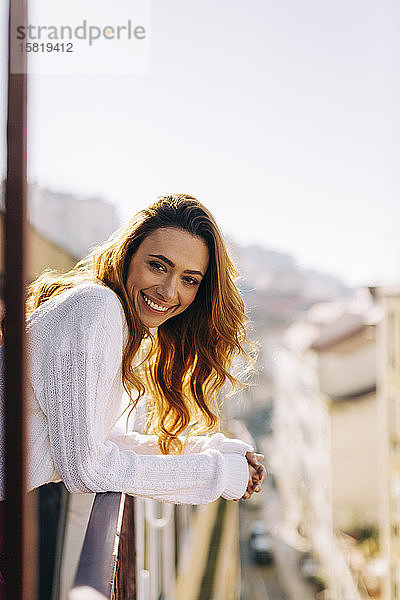 Porträt einer glücklichen jungen Frau auf dem Balkon