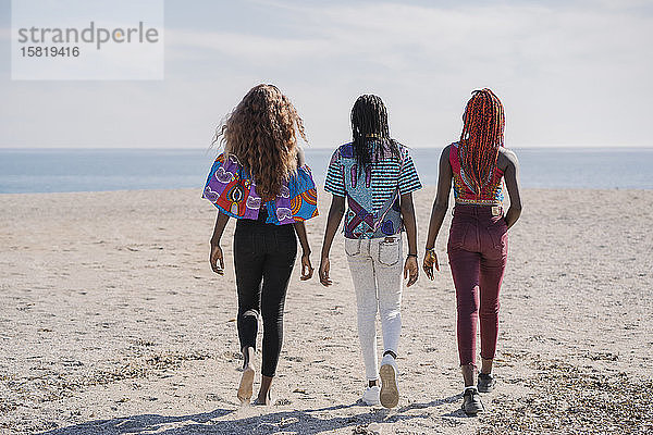 Rückansicht der am Strand spazieren gehenden Teenager-Freundinnen