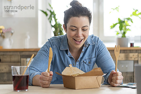 Porträt einer Frau  die am Tisch sitzt und mit Holzbesteck isst