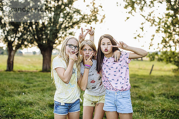 Porträt von verspielten Mädchen  die im Freien lustige Gesichter ziehen