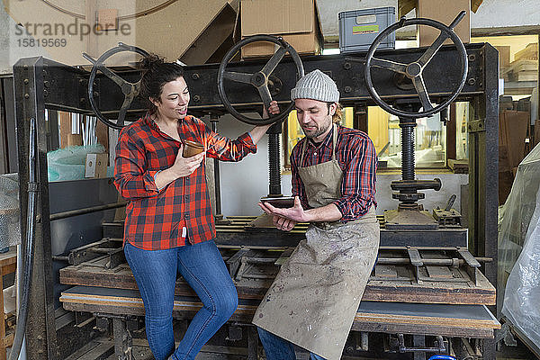 Handwerkerin und Handwerker mit Tablette diskutieren in ihrer Werkstatt