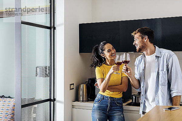Glückliches junges Paar trinkt zu Hause gemeinsam Wein in der Küche