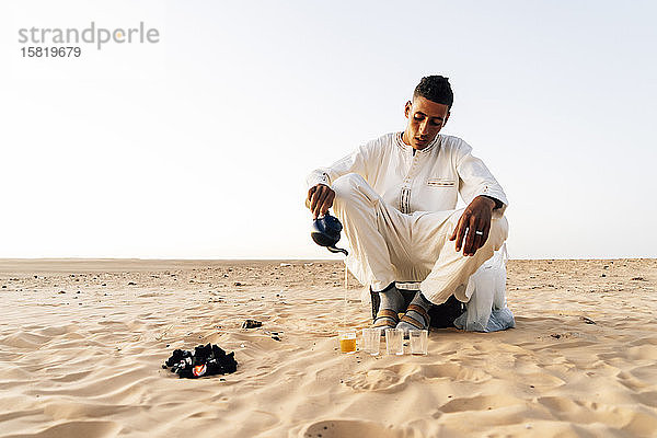 Mann gießt Tee in Gläser in der Wüste Sahara  Tindouf  Algerien