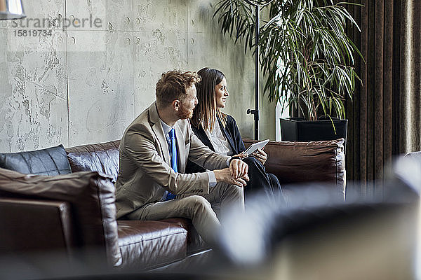 Geschäftsmann und Geschäftsfrau sitzen während eines Treffens in der Hotellobby auf einer Couch