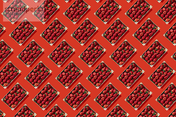 Reihen von Erdbeeren in Holzkisten vor rotem Hintergrund