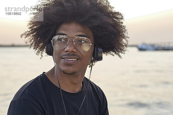 Porträt eines jungen Mannes  der eine Brille trägt und Musik hört