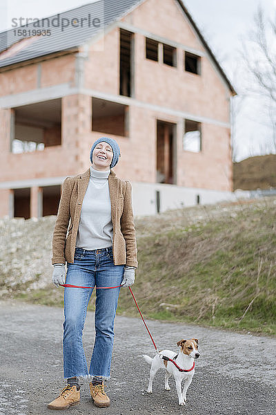 Porträt einer glücklichen  reifen Frau  die mit ihrem Hund Gassi geht