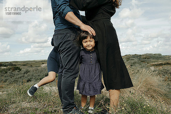 Porträt eines kleinen Mädchens  das zwischen Vater und Mutter in den Dünen steht  Den Haag  Niederlande