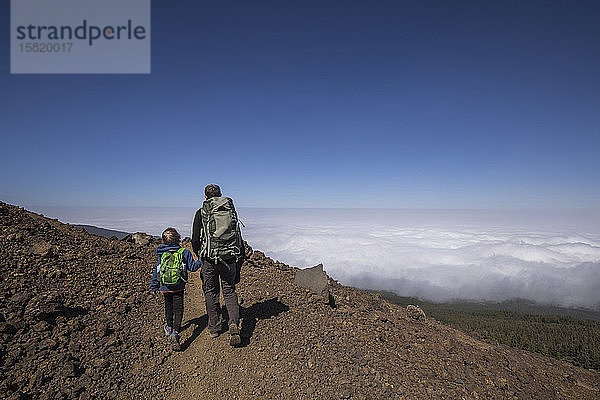 Rückansicht eines Vaters mit seinem Sohn beim Trekking in der Gegend von Arenas Negras  Teide-Nationalpark  Teneriffa