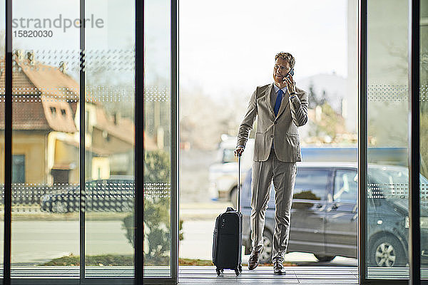 Geschäftsmann am Telefon beim Betreten des Hotels