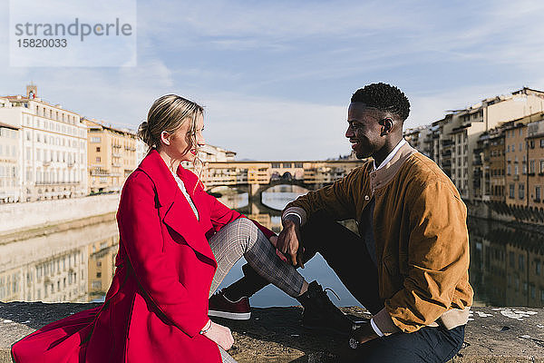 Lächelndes junges Paar sitzt auf einer Brücke in der Stadt Florenz  Italien