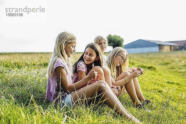 Mädchen  die auf einem Feld auf dem Land sitzen